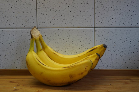 Bunch of bananas on a wooden table in a modern kitchen.の写真素材