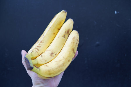 banana in hand on a black background. Healthy food concept.の写真素材