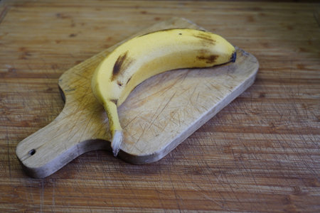 banana on a wooden cutting board on a wooden kitchen table.の写真素材