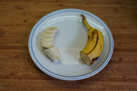 Sliced banana on a white plate on a wooden table.の写真素材