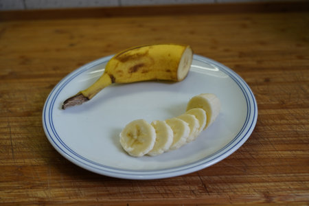 Sliced banana on a white plate on a wooden table.の写真素材