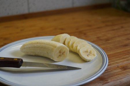 Peeled bananas on a plate with a knife on a wooden tableの写真素材