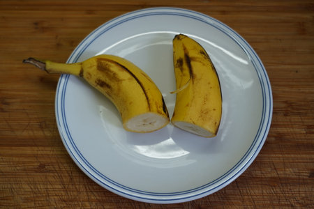 Ripe banana on a white plate on a wooden table. Close-up.の写真素材