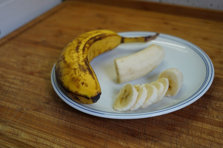 Banana slices on a white plate on a wooden table. Selective focus.の写真素材