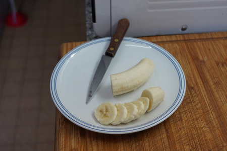 Sliced banana on a plate with a knife in the kitchenの写真素材