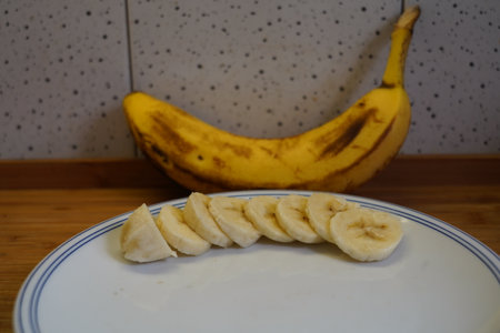 Sliced banana on a white plate on a wooden table.の写真素材