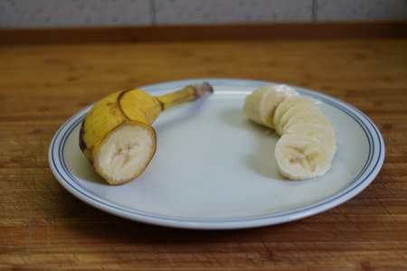 Sliced banana on a white plate on a wooden table.の写真素材