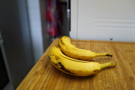 Bunch of bananas on a wooden table in the kitchen. Selective focus.の写真素材