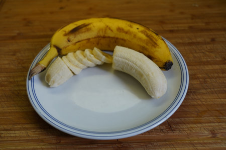Banana and yogurt on a white plate on a wooden table.の写真素材