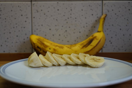 Banana slices on a white plate in the kitchen. Selective focus.の写真素材