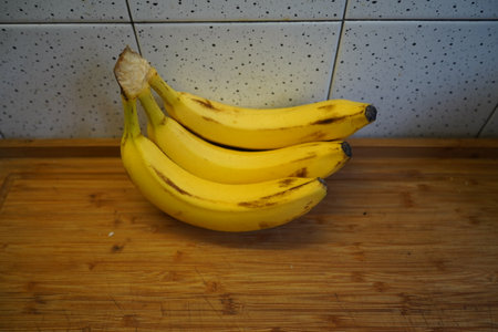 Bunch of bananas on a chopping board in a rustic kitchenの写真素材