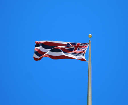 Hawaii State Flag waves in the wind against Blue Background.  Taken outside Hawaiis state capitolの写真素材