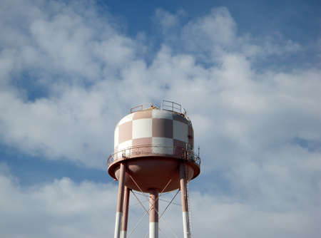 a large Checkered colored water tower against a blue cloudy sky の写真素材