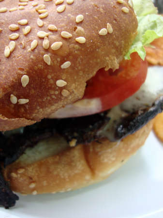 close up of  on white plate portabella mushroom burger with lettuce tomato and seseme bunの写真素材