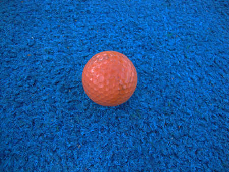 well used Orange golf ball on blue artificial turfの写真素材