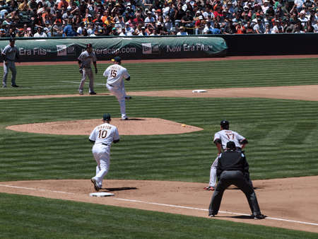 Giants 0 Vs. Athletics 3: Athletics Ben Sheets lifts leg to pitch with runners on 1st and 3rd taking leads.  Taken May 23 2010 at the Coliseum Oakland California.のeditorial素材