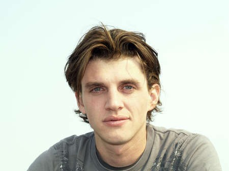 Portrait head shot of a handsome man twenty some, Actor Tony Wyban, with blue eyes and white sky backgroundの写真素材