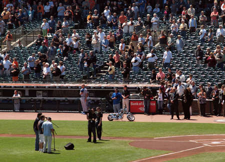 Kanasa City Royals vs Oakland A's:Three men sing the national anthem in front of a camera on the field as Cubs Players and San Francisco fans stand with hats removed during the national anthem before the start of the game.  August 12 2010 at the ATT Park のeditorial素材