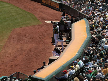 Royals vs. Athletics: Oakland Athletics Dugout and fans behind them.  Kevin Kouzmanoff can be seen sitting on a water cooler with his hat off. Taken on August 4 2010 at Coliseum in Oakland California.のeditorial素材