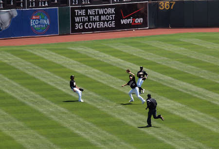 Royals vs. Athletics: Athletics run down ball in outfield with Mark Ellis opening glove to make catch.  Coco Crisp and Rajai Davis give him room to make catch.  Taken on August 4 2010 at Coliseum in Oakland California.のeditorial素材