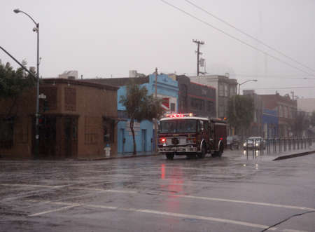 SFFD Fire Truck races down fourth street in the rain with sirens and lights on.  San Francisco...