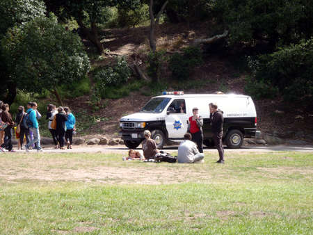 SFPD van slowly drives by youthful people in Golden Gate park.  Taken August 1, 2010 in Golden Gate Park San Francisco, CA.のeditorial素材