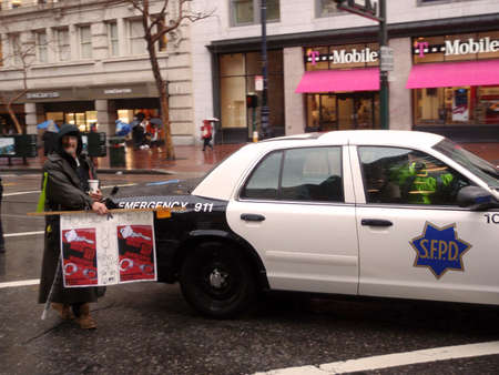 Protester holds 'House Keys, not handcuff' sign in front of SFPD car on rainy day during a march down Market Street.  Taken January 20, 2010 San Francisco California.のeditorial素材