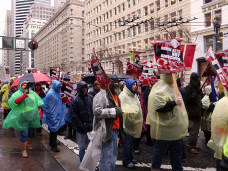 Protester holds 'House Keys, not handcuff' sign  as they march down market street on rainy day.  Taken January 20, 2010 San Francisco California.のeditorial素材