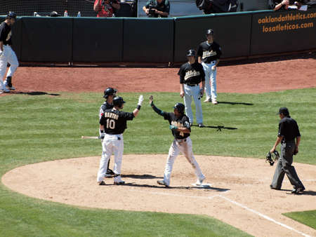 Blue Jays vs. Athletics: Athletics Coco Crisp raises hand to high five Daric Barton as he crosses homeplate after hitting a homerun.  Taken on August 18 2010 at Coliseum in Oakland California.のeditorial素材