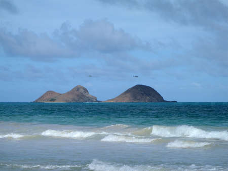 HONOLULU - NOVEMBER 30: Military Helicopters fly on the mokulua islands with waves crashing towards the shore taken November 30, 2010 Waimanalo, Hawaii のeditorial素材