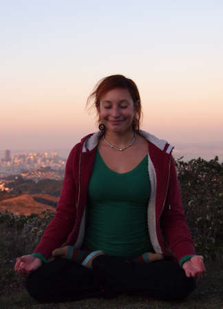Beautiful Lady sits in seated meditation with San Francisco in Background.の写真素材