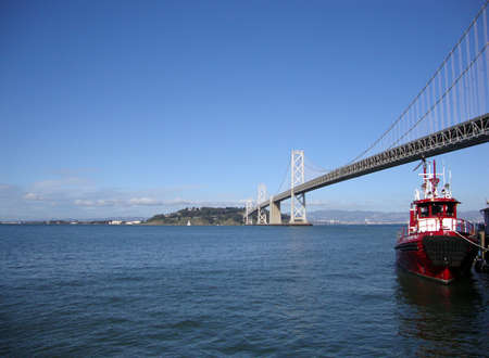 Fireboat docked in front of the San Francisco-Oakland Bay Bridge looking towards the east bay on a nice day.の写真素材