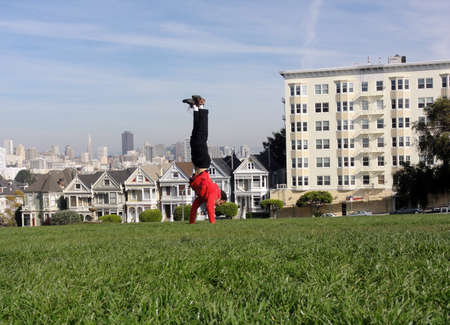Handstanding in front of the painted ladies buildings of San Francisco, Californiaの写真素材