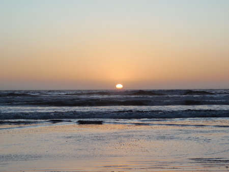 Sunset over the crashing waves on Morro Beach in California.の写真素材