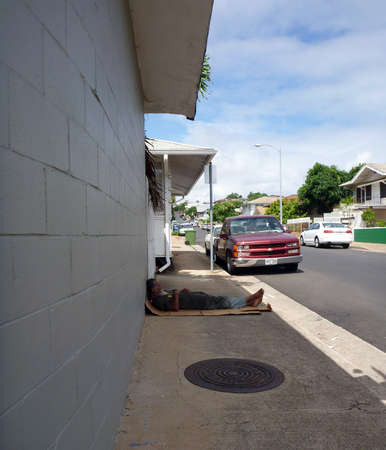 HONOLULU - JUNE 20: Homeless man sleeps on top of cardboard box on sidewalk next to building in Kapahulu, Honolulu, June 20, 2012 のeditorial素材