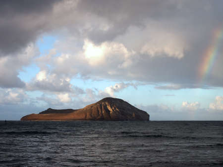 Rainbow goes into the water next to rabbit island in Waimanalo Bay on the windward side of Oahu, Hawaii の写真素材