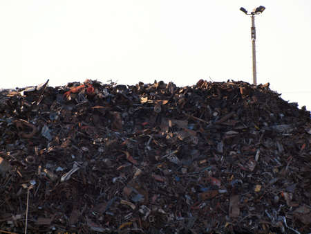 Large pile of metal scrapes trash with lights on a pole above の写真素材