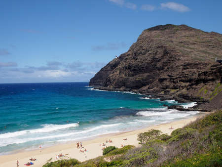 People hang out at Makapuu Beach with Lighthouse in view  on a nice day on Oahuの写真素材
