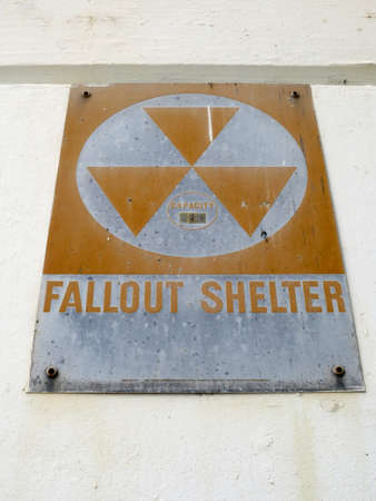 Old Fallout Shelter Sign from the cold war era slowly rusts as it hangs on wall.の写真素材