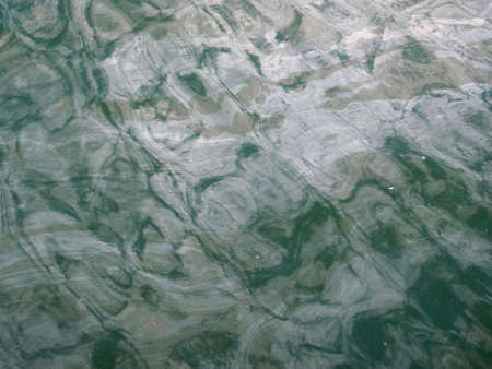 Oil slicked turquoise water with a reflective pattern.