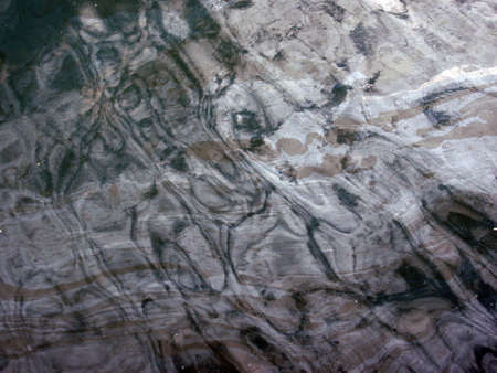 Oil slicked dark water with a reflective pattern.