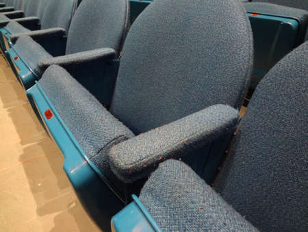 Curved Rows of Light Blue Cloth Seat with armrests in a theater.  With Number 31 visible on seat.