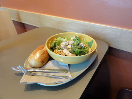 Asian Sesame Chicken Salad greens and half loaf of bread on table with fork and knife on top of paper napkins in a cafe.                               の写真素材