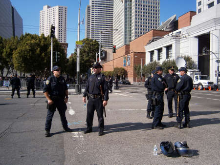 SAN FRANCISCO, CA - OCTOBER 25: SFPD Police officers stand on street talking as protesters of Marijuana rights stand behind fence along Howard street on October 25, 2011 in San Francisco.のeditorial素材