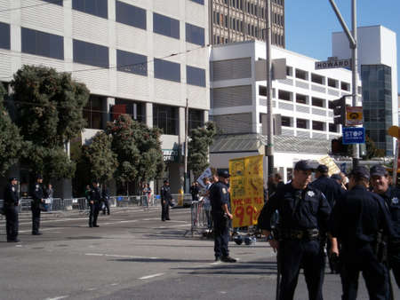 SAN FRANCISCO, CA - OCTOBER 25: SFPD Police officers stand on street as protesters hold sign saying 'We Are the 99%' stand behind fence along Howard and 3rd street on October 25, 2011 in San Francisco.のeditorial素材
