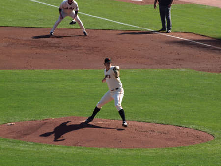 SAN FRANCISCO, CA - OCTOBER 19: San Francisco Giants vs. Philadelphia Phillies: Pitcher Matt Cain steps forward to throw pitch with shadow casting below him, 1st baseman and umpire in the background, game three of the NLCS 2010 taken October 19, 2010 AT&Tのeditorial素材