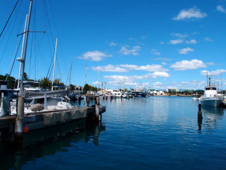 Boats of various sizes docked in Kewalo Basin Harbor in Honolulu with Kakaako in the distance on a beautiful day. の写真素材