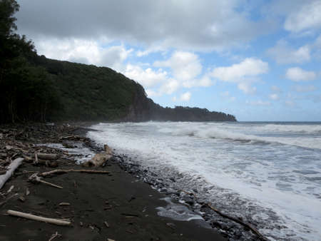 Pololu Valley black sand beach in Big island, Hawaii surrounded by Valley cliffs and the dramatic northeastern coastline.の写真素材