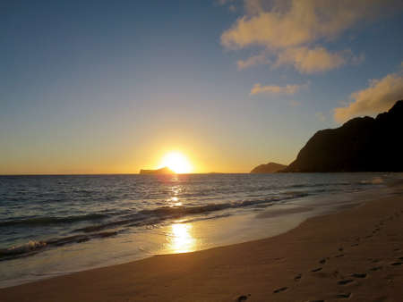 Early Morning Sunrise on Waimanalo Beach over Rabbit Island bursting over the island on Oahu, Hawaii.  With Lighthouse on mountain in distance.の写真素材