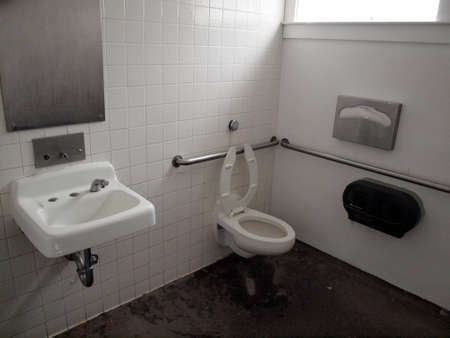 Inside Public Bathroom with sink, toilet, soap dispenser, and handicap railings on Angel Island, California.の写真素材